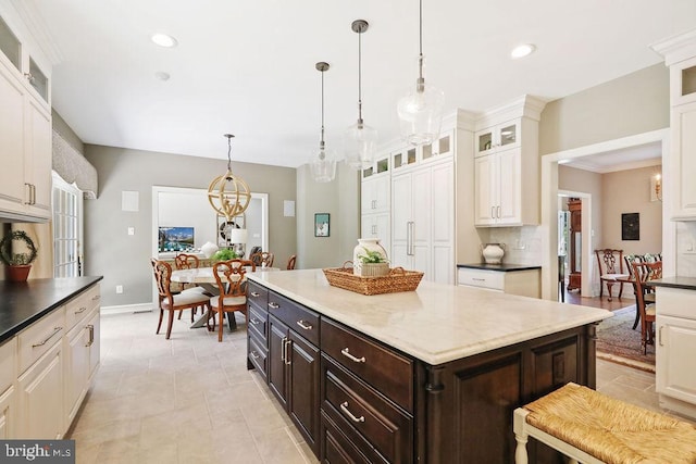 kitchen featuring decorative backsplash, dark brown cabinetry, decorative light fixtures, an inviting chandelier, and a kitchen island