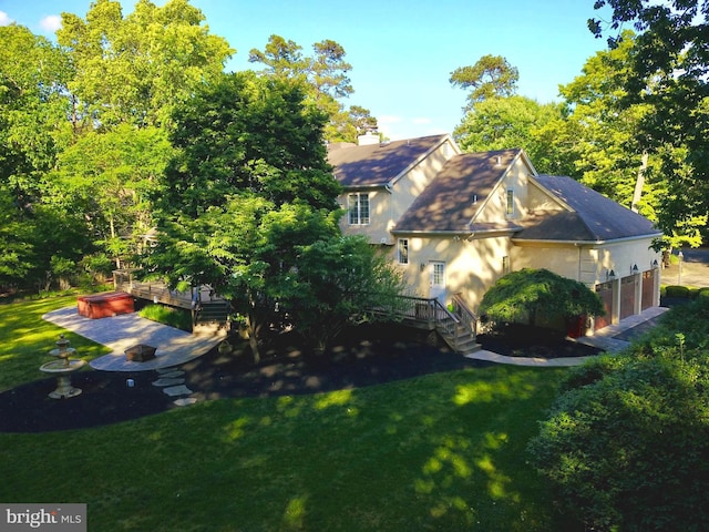 view of home's exterior with a jacuzzi, a patio, a lawn, and a wooden deck