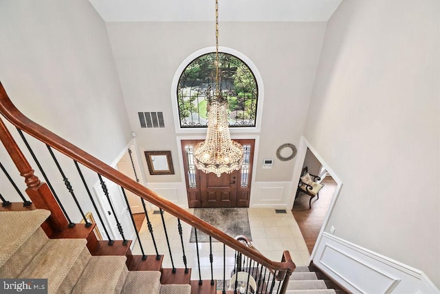 entrance foyer featuring hardwood / wood-style floors, a towering ceiling, and a chandelier