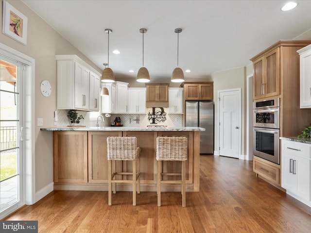 kitchen with white cabinetry, stainless steel appliances, light hardwood / wood-style flooring, backsplash, and pendant lighting