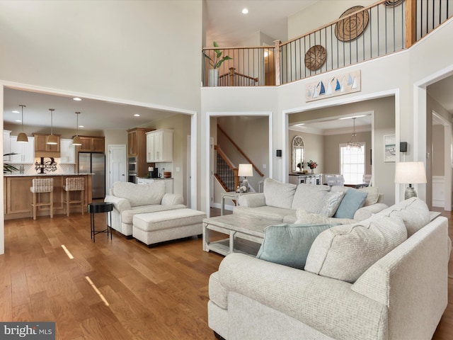 living room with crown molding, hardwood / wood-style floors, and a towering ceiling