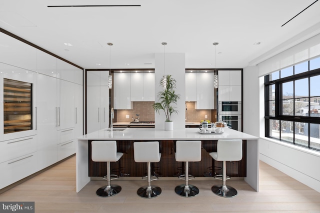 kitchen with a kitchen breakfast bar, an island with sink, and pendant lighting