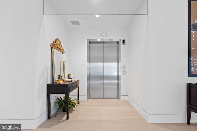 hall with elevator and light hardwood / wood-style flooring