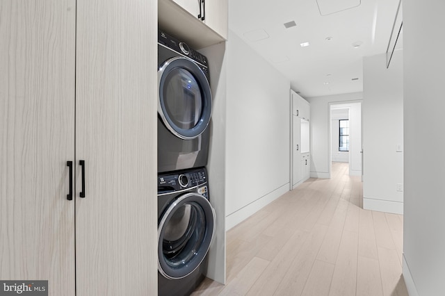 clothes washing area with stacked washer and dryer and light hardwood / wood-style flooring