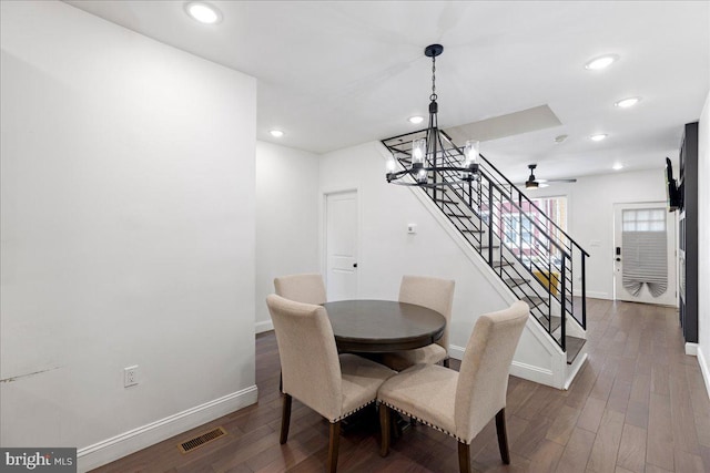 dining space with ceiling fan with notable chandelier and dark hardwood / wood-style floors