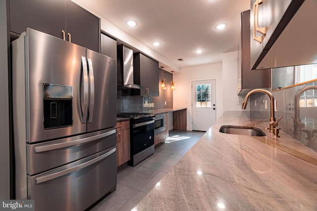 kitchen with sink, wall chimney range hood, light stone counters, decorative backsplash, and appliances with stainless steel finishes