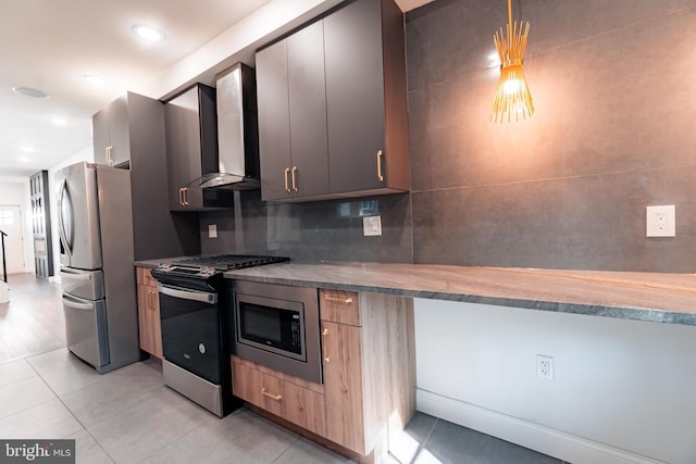 kitchen featuring tasteful backsplash, wall chimney exhaust hood, stainless steel appliances, hanging light fixtures, and light tile patterned flooring