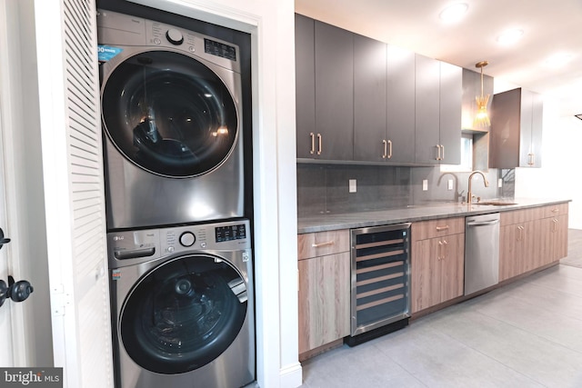 laundry room with sink, light tile patterned floors, beverage cooler, and stacked washer / drying machine