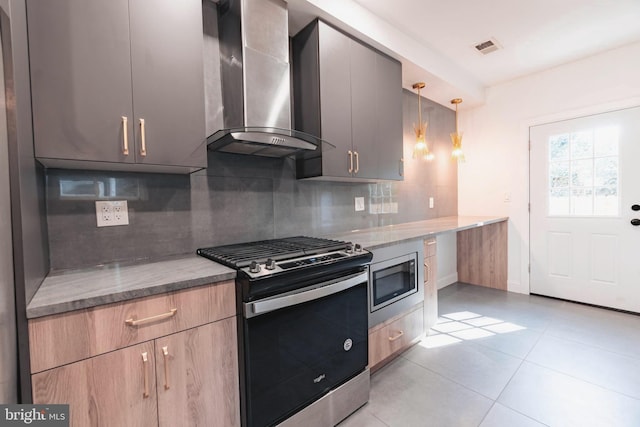 kitchen with stainless steel appliances, wall chimney range hood, dark stone countertops, pendant lighting, and decorative backsplash