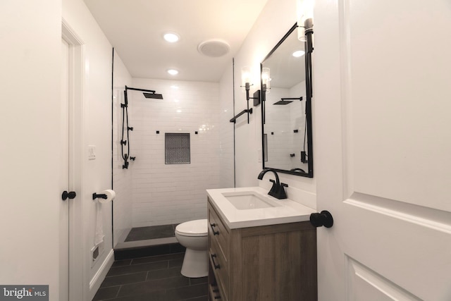 bathroom with a tile shower, tile patterned floors, vanity, and toilet