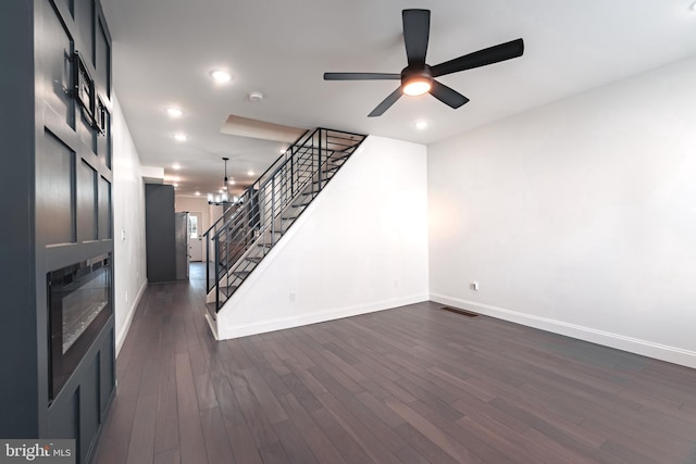 unfurnished living room featuring dark hardwood / wood-style flooring and ceiling fan with notable chandelier