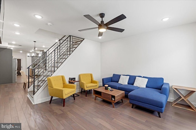 living room with ceiling fan with notable chandelier and dark hardwood / wood-style floors