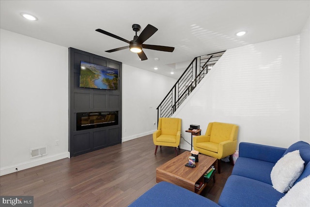 living room featuring ceiling fan and dark wood-type flooring