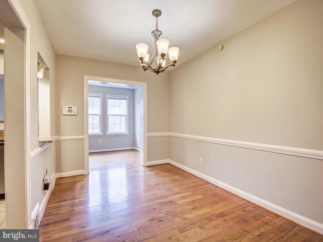 spare room with light wood-type flooring and a chandelier