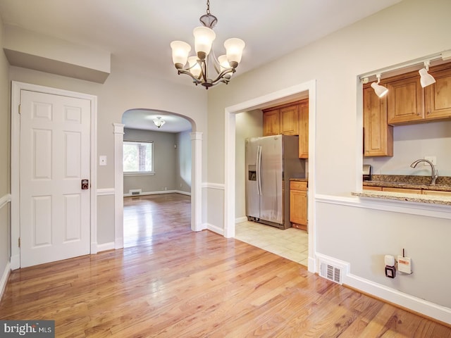 kitchen with decorative light fixtures, light wood-type flooring, stainless steel fridge with ice dispenser, and an inviting chandelier