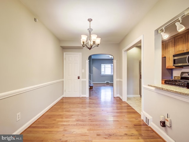 unfurnished dining area featuring a chandelier and light hardwood / wood-style floors