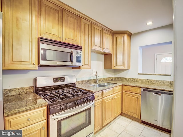 kitchen featuring light stone countertops, sink, light tile patterned floors, and appliances with stainless steel finishes