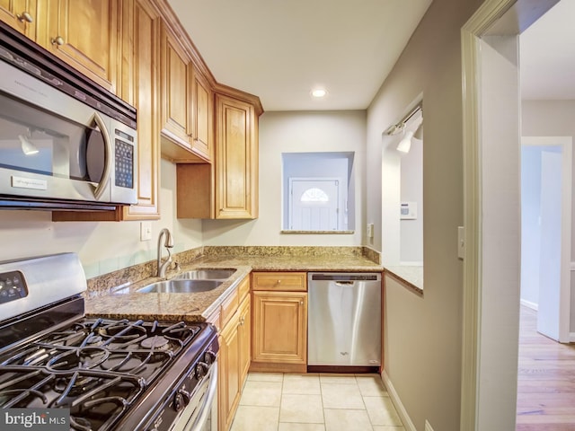 kitchen with light stone counters, sink, appliances with stainless steel finishes, and light hardwood / wood-style flooring