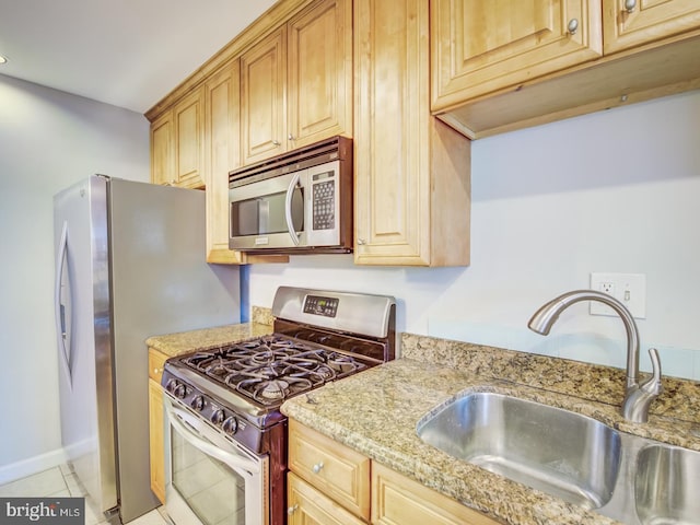 kitchen featuring light stone counters, sink, light tile patterned floors, and stainless steel appliances