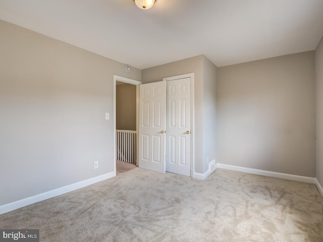 unfurnished bedroom with light colored carpet and a closet