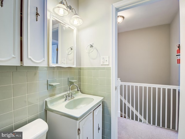 bathroom featuring vanity, tile walls, and toilet