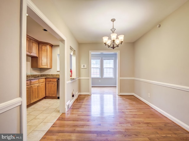 unfurnished dining area featuring light hardwood / wood-style flooring and a notable chandelier