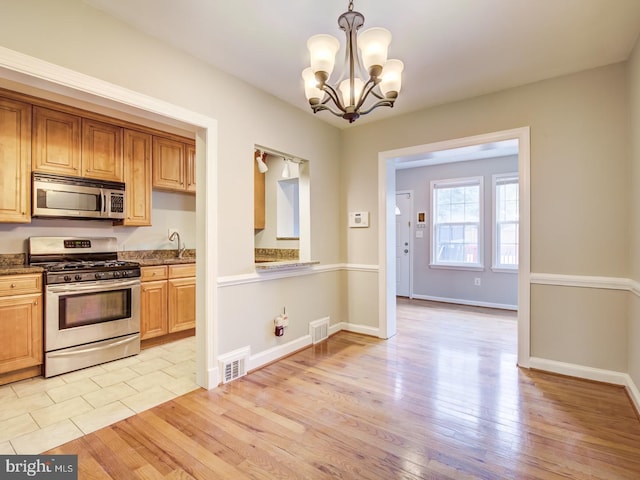 kitchen with decorative light fixtures, light wood-type flooring, appliances with stainless steel finishes, and an inviting chandelier