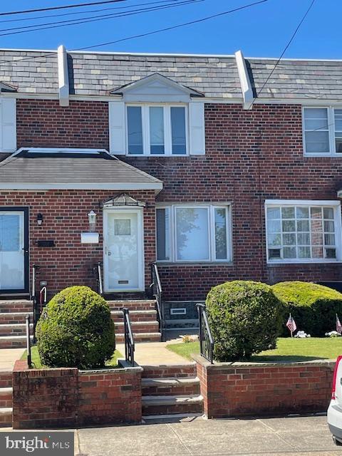 townhome / multi-family property featuring entry steps, a high end roof, mansard roof, and brick siding