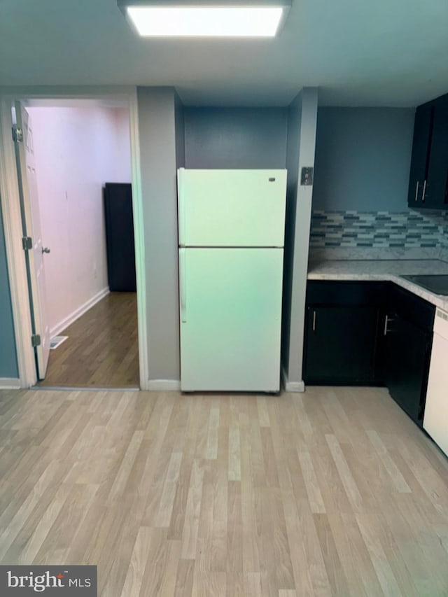 kitchen featuring white refrigerator, sink, light wood-type flooring, and backsplash