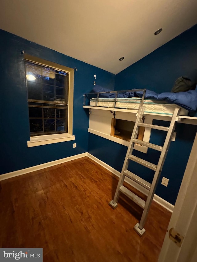 unfurnished bedroom featuring hardwood / wood-style floors and vaulted ceiling