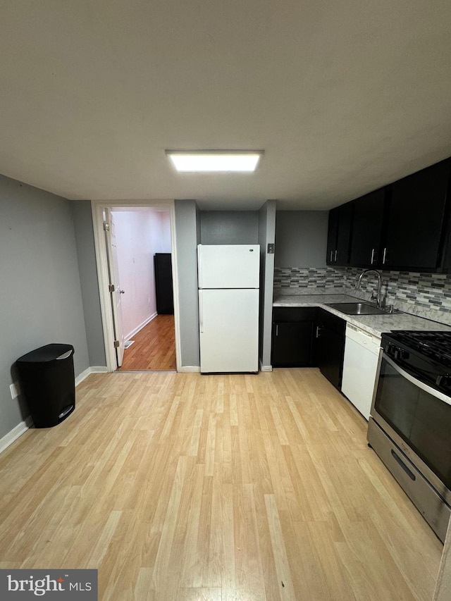 kitchen featuring decorative backsplash, white appliances, light hardwood / wood-style floors, and sink