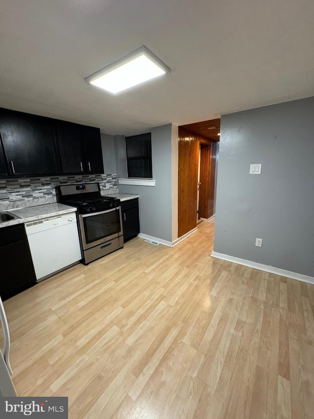 kitchen featuring decorative backsplash, dishwasher, stainless steel range oven, and light hardwood / wood-style flooring