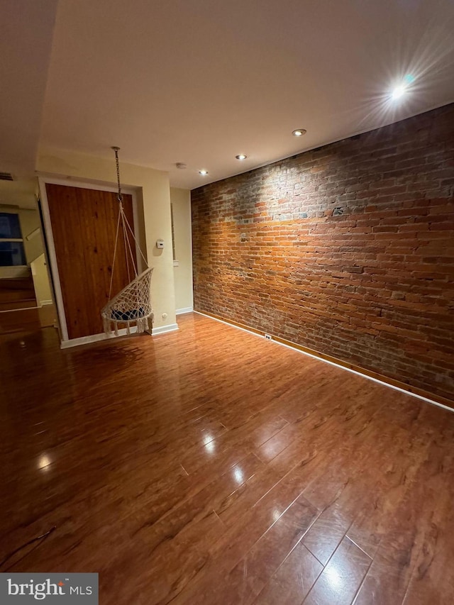 unfurnished room featuring dark wood-type flooring and brick wall