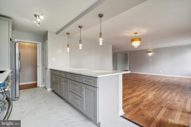 kitchen featuring gray cabinets, light hardwood / wood-style floors, kitchen peninsula, stainless steel appliances, and a chandelier