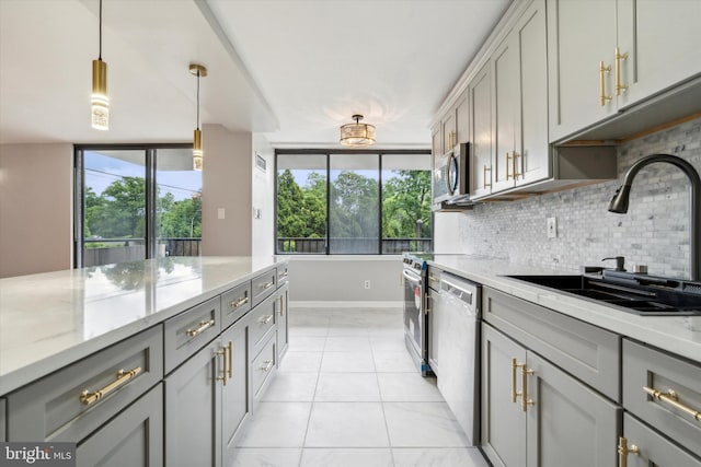 kitchen with gray cabinetry, light stone countertops, sink, stainless steel appliances, and tasteful backsplash