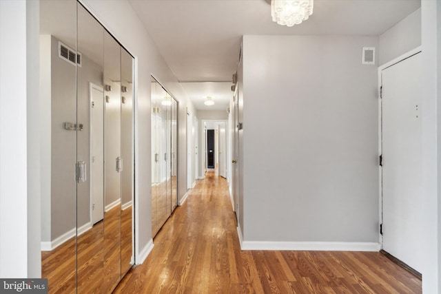 hallway featuring light hardwood / wood-style floors and an inviting chandelier