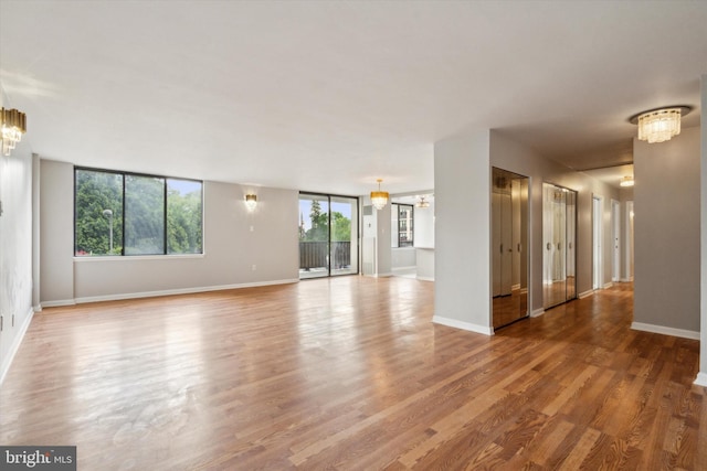 unfurnished room featuring hardwood / wood-style flooring, a healthy amount of sunlight, and a chandelier