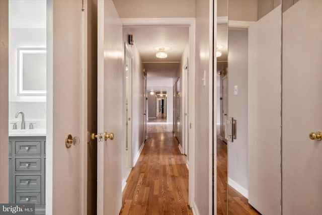 corridor with dark hardwood / wood-style flooring and sink