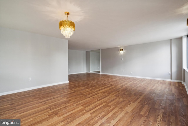 unfurnished room with hardwood / wood-style floors and a notable chandelier