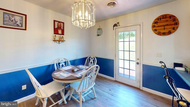 dining space featuring hardwood / wood-style flooring and a notable chandelier