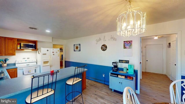 kitchen featuring pendant lighting, white appliances, light hardwood / wood-style flooring, and a notable chandelier