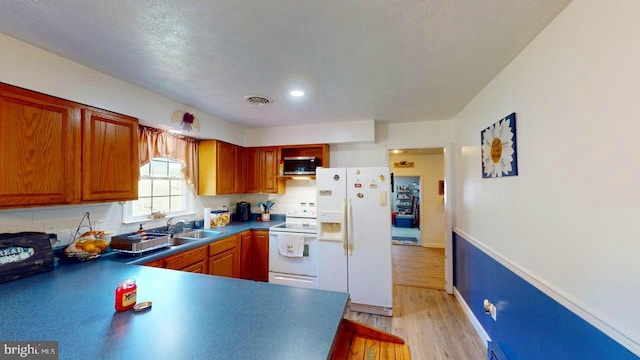 kitchen featuring a textured ceiling, sink, white appliances, and light wood-type flooring