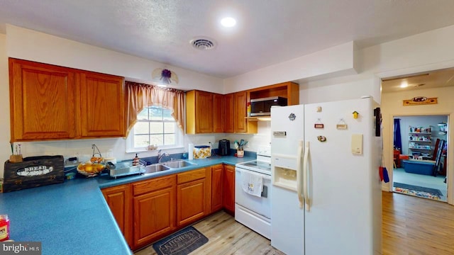 kitchen with tasteful backsplash, light hardwood / wood-style flooring, white appliances, and sink