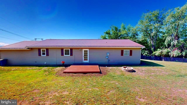 rear view of house with a yard and an outdoor fire pit