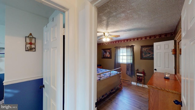 bedroom featuring hardwood / wood-style flooring, ceiling fan, a textured ceiling, and a baseboard radiator