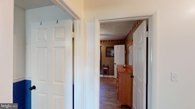 corridor featuring wood-type flooring and a textured ceiling