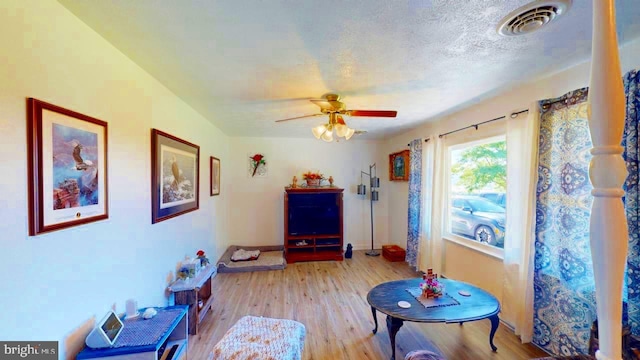 interior space with ceiling fan, light hardwood / wood-style floors, and a textured ceiling