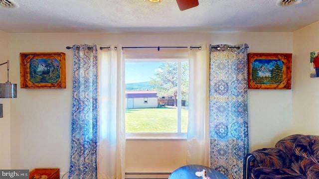 interior space featuring a textured ceiling, baseboard heating, and ceiling fan