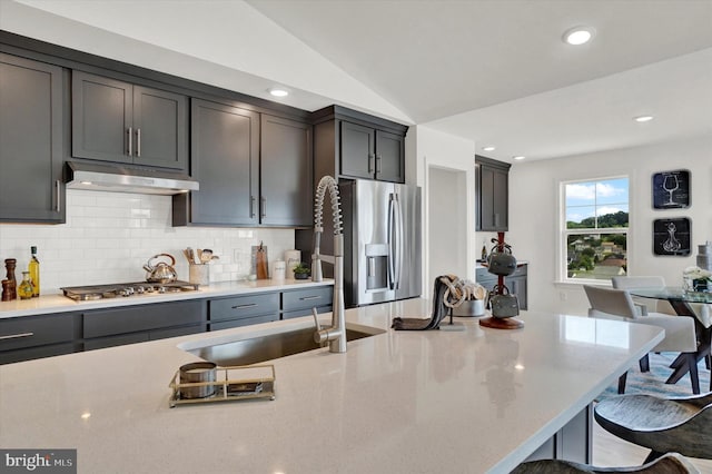 kitchen with sink, a kitchen breakfast bar, tasteful backsplash, vaulted ceiling, and appliances with stainless steel finishes