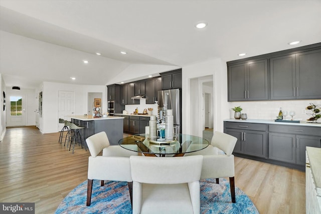 dining space featuring light hardwood / wood-style flooring and vaulted ceiling